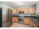 Well lit kitchen featuring stainless steel appliances, wooden cabinets, and dark countertops at 1911 Almond Hills Dr, Charlotte, NC 28262