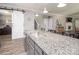 Kitchen island with granite countertop, stainless steel sink, and pendant lighting, adjacent to stairs and sliding barn door at 2207 Atwell Glen Ln, Pineville, NC 28134