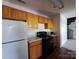 Small kitchen with wood cabinets, black appliances, and a spiral staircase in the background at 2527 Carya Pond Ln, Charlotte, NC 28212