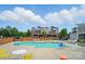 Relaxing community pool area with lounge chairs, tables, and shady seating areas with multi-story homes in the background at 2533 Ensemble Ct, Charlotte, NC 28262