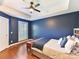 Beautiful bedroom featuring dark blue accent wall, hardwood floors, and tray ceiling with a modern ceiling fan at 2621 Huntman Way, Charlotte, NC 28226