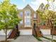 Brick townhome featuring an attached garage, stoop entry, black iron railings, bay window, and mature landscaping at 2621 Huntman Way, Charlotte, NC 28226