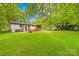 Spacious backyard with a lush lawn, mature trees, and a deck, creating a serene outdoor space at 509 Carole Ln, Charlotte, NC 28214