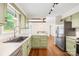 Corner view of kitchen with light green cabinets and stainless steel appliances at 509 Carole Ln, Charlotte, NC 28214