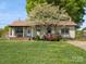 Charming home featuring a cozy porch, complemented by vibrant azaleas and a mature dogwood tree at 714 S 8Th St, Bessemer City, NC 28016
