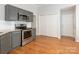 Renovated kitchen features stainless steel appliances, gray cabinets and hardwood floors, with access to laundry area at 8718 Rittenhouse Cir, Charlotte, NC 28270