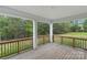 Covered porch featuring wood flooring, wood railings, and white pillars, providing a relaxing outdoor space with wooded view at 8756 Sherrills Ford Rd, Sherrills Ford, NC 28673