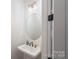 Stylish powder room featuring a round mirror, modern lighting fixture, and a sleek wall-mounted sink at 8756 Sherrills Ford Rd, Sherrills Ford, NC 28673