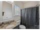 Bathroom featuring a granite countertop vanity, patterned shower curtain, toilet, and window with blinds at 9867 Travertine Trl, Davidson, NC 28036