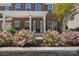 Inviting front porch with vibrant pink flowers, lush plants, and a charming seating area at 9867 Travertine Trl, Davidson, NC 28036