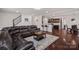 Living room featuring a brown leather sectional sofa, wood flooring, and an open view of the kitchen and dining area at 9867 Travertine Trl, Davidson, NC 28036