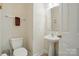 Bathroom with white walls, pedestal sink, decorative mirror, toilet, and a white door at 10056 Paisley Dr, Charlotte, NC 28269