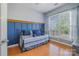Cozy bedroom with a blue accent wall, wooden floors, and a large window for natural light at 10354 Scotland Ave, Fort Mill, SC 29707