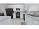 Efficient kitchen featuring white cabinets, black appliances, and light countertops with a view of the laundry area at 10526 Hill Point Ct, Charlotte, NC 28262