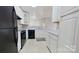 A bright kitchen featuring black appliances, white cabinets, light countertops, and an eat-in bar area at 10526 Hill Point Ct, Charlotte, NC 28262
