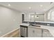 Open-concept kitchen with stainless steel dishwasher, white cabinets, and a bar overlooking the living area at 109 W Poplar St, Stanley, NC 28164