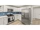 Modern kitchen featuring stainless steel appliances, white cabinets, and a stylish blue tiled backsplash at 109 W Poplar St, Stanley, NC 28164