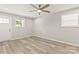 Neutral living room featuring wood-look floors, a ceiling fan, a white door, and ample natural light at 109 W Poplar St, Stanley, NC 28164