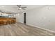 Spacious living room with wood-look flooring, ceiling fan, and bar area open to the modern kitchen at 109 W Poplar St, Stanley, NC 28164