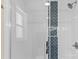 Walk in shower with white tiled walls and a decorative blue accent stripe and modern fixtures at 109 W Poplar St, Stanley, NC 28164