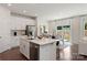 Modern kitchen with a central island, stainless steel appliances, sleek white cabinetry, and an adjacent dining area at 117 Vaquaro Dr, Mooresville, NC 28115