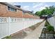 Townhome backyard with white fence, sidewalk, and garden beds at 1218 Green Oaks Ln # E, Charlotte, NC 28205