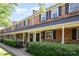 Charming brick townhome with a covered front porch, lush landscaping, and classic black shutters at 1218 Green Oaks Ln # E, Charlotte, NC 28205