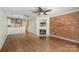 Hardwood-floored living room with brick accent wall and a cozy fireplace, open to the dining area at 1218 Green Oaks Ln # E, Charlotte, NC 28205