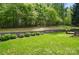 Lush green backyard featuring manicured lawn, trees, and a stone retaining wall at 12531 Morning Creek Ln, Charlotte, NC 28214