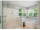 Bathroom with a glass-enclosed shower and a separate soaking tub, all naturally lit by large windows at 12531 Morning Creek Ln, Charlotte, NC 28214