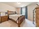 Cozy bedroom with wooden furniture, a patterned blanket, and blue curtains allowing natural light at 127 Slip Shot Ln, Troutman, NC 28166