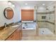 Bathroom featuring double sink vanity, soaking tub, glass shower, and a round mirror at 135 Coronilla Rd, Mooresville, NC 28117
