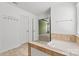 Bathroom with a soaking tub and tile surround, plus a door leading to the primary bedroom at 1617 Post Ct, Gastonia, NC 28054