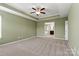 Spacious carpeted bedroom with tray ceiling and ceiling fan, leading into the ensuite bathroom at 1617 Post Ct, Gastonia, NC 28054