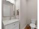 Powder room with marble countertop, framed mirror, and hardwood floors, offering a touch of elegance at 17728 Jetton Green Loop, Cornelius, NC 28031