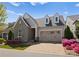 Charming home boasts stone accents, dormer windows, and a well-manicured front yard with colorful flowers at 17728 Jetton Green Loop, Cornelius, NC 28031