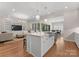 Open kitchen with stainless steel sink, island with seating, flows into a living room with built-in bookshelves at 17728 Jetton Green Loop, Cornelius, NC 28031