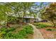 Charming cottage with a wooden walkway and a front porch with a wooded landscaped yard and teal front doors at 2106 4Th Ne St, Hickory, NC 28601