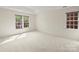 A carpeted and light bedroom with two windows offers a simple and comfortable space to sleep and relax at 213 Walnut Point Dr, Matthews, NC 28105