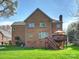 Rear exterior view of a brick home, showcasing the deck, landscaped yard, and architectural details of the property at 213 Walnut Point Dr, Matthews, NC 28105