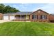 Brick home featuring a two-car garage, a cozy front porch, lush green lawn, and vibrant yellow door at 2459 Glenridge Dr, Gastonia, NC 28054