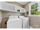 Bright laundry room features a washer and dryer, shelving, and a window at 2459 Glenridge Dr, Gastonia, NC 28054