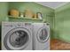 Well-lit laundry room featuring modern washer and dryer, decorative shelves, and fresh green walls at 3036 Palm Ave, Charlotte, NC 28205