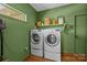 Functional laundry room with modern washer and dryer, complemented by a shelf with decor and green painted walls at 3036 Palm Ave, Charlotte, NC 28205