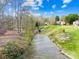 Scenic waterfront view featuring lush green grass and a variety of trees on a sunny day at 32 Heritage Ln, Shelby, NC 28150