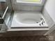 A modern bathroom with an elegant white bathtub under a window at 4038 Gardenia Dr # 0114, Harrisburg, NC 28075