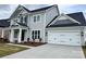 The home has an attached two-car garage with a concrete driveway, coach lights and a gray exterior at 4038 Gardenia Dr # 0114, Harrisburg, NC 28075
