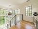 Hallway with hardwood floors, industrial metal banister, modern light fixture and large windows looking out into the yard at 410 Mcalway Rd, Charlotte, NC 28211