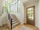 Inviting foyer with a staircase leading up, featuring a large window, carpeted steps, and hardwood flooring near the wooden front door at 410 Mcalway Rd, Charlotte, NC 28211