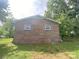 Side exterior view of a brick home showcasing a well-maintained lawn and a sturdy, classic design with a gable roof at 4230 Old Brittain Rd, Hickory, NC 28602
